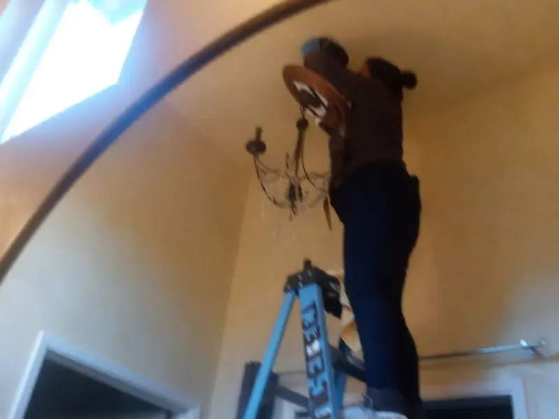 Electrician installing a chandelier in a Byron residence
